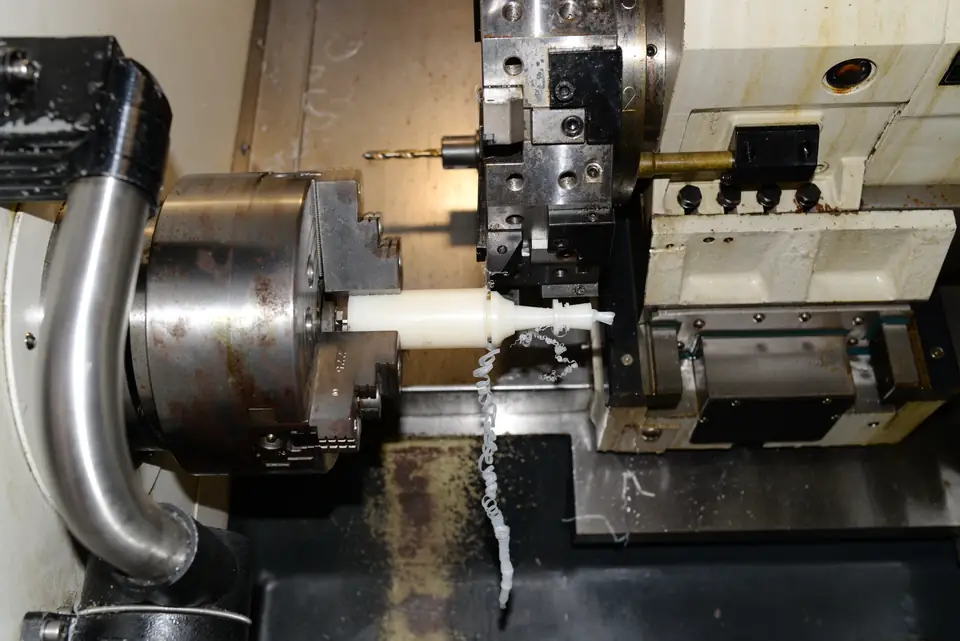 CNC lathe turning a plastic part, live tooling with a drill in the turret